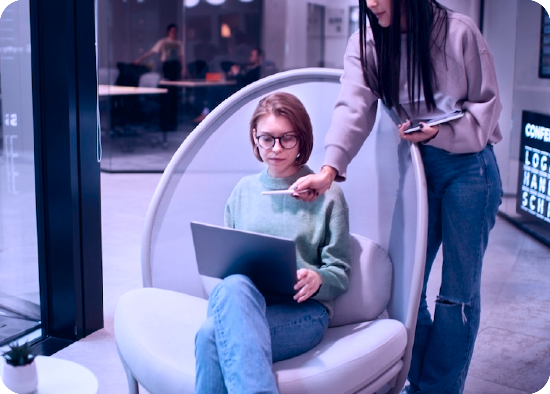 Colleague pointing to a teammate’s laptop in a modern office, illustrating Octopyd’s human-plus-AI hiring mission